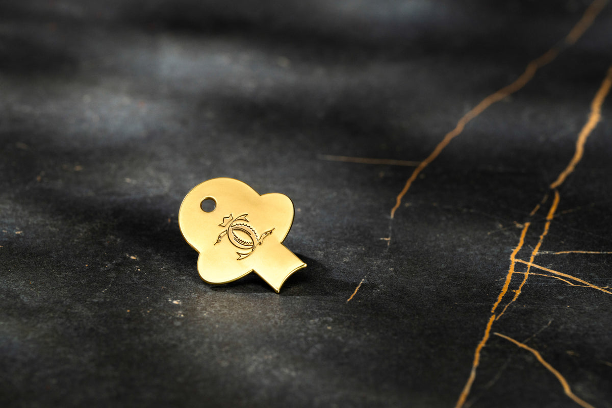 Small gold Cavian branded accessory featuring an engraved logo on an elegant black marble surface.