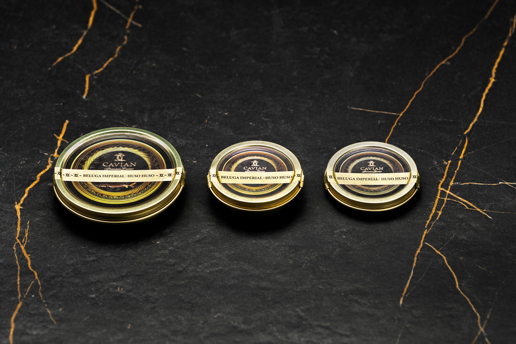 Three Cavian Beluga Imperial Huso Huso caviar tins in different sizes with signature black and gold packaging.