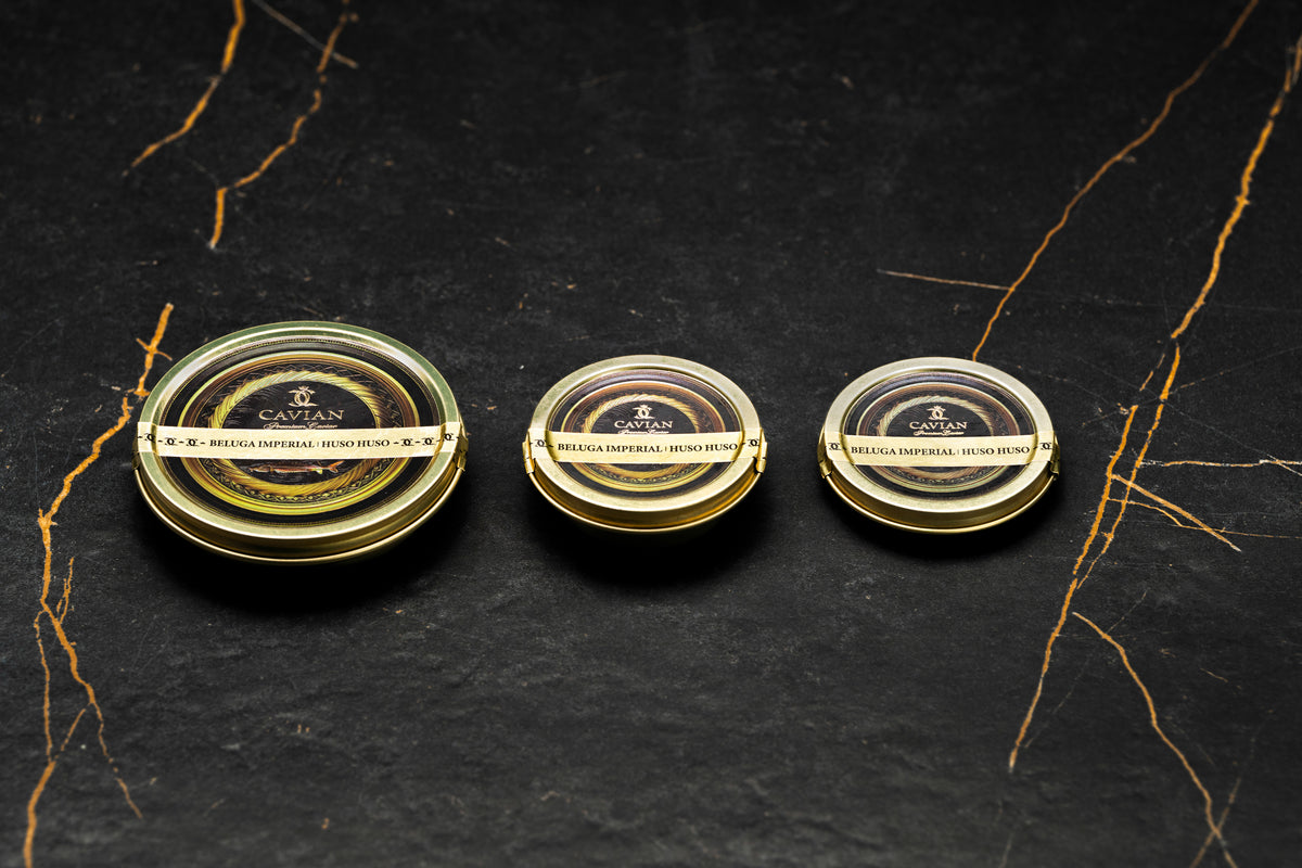 Three Cavian Beluga Imperial Huso Huso caviar tins in different sizes with signature black and gold packaging.