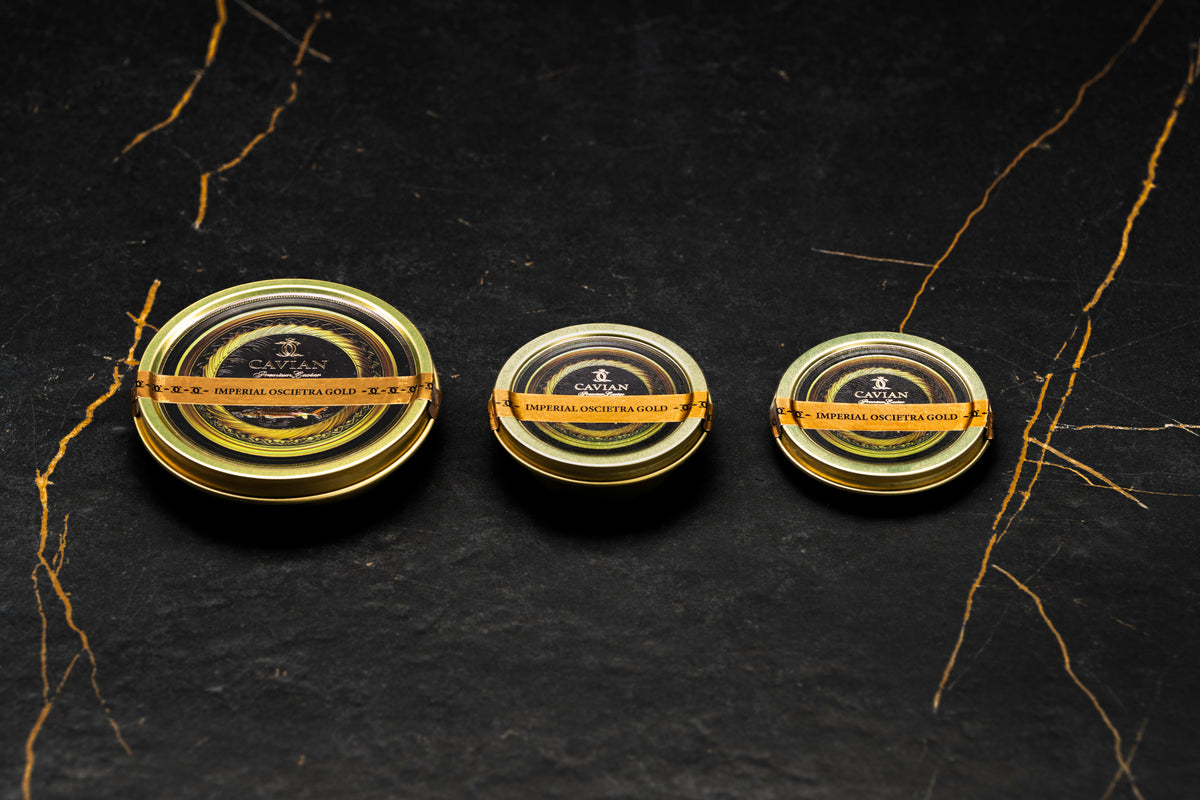 Three Cavian Imperial Oscietra Gold caviar tins in different sizes with signature black and gold packaging.