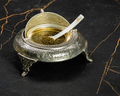 Open engraved silver caviar serving bowl filled with golden caviar and a Cavian mother-of-pearl spoon.
