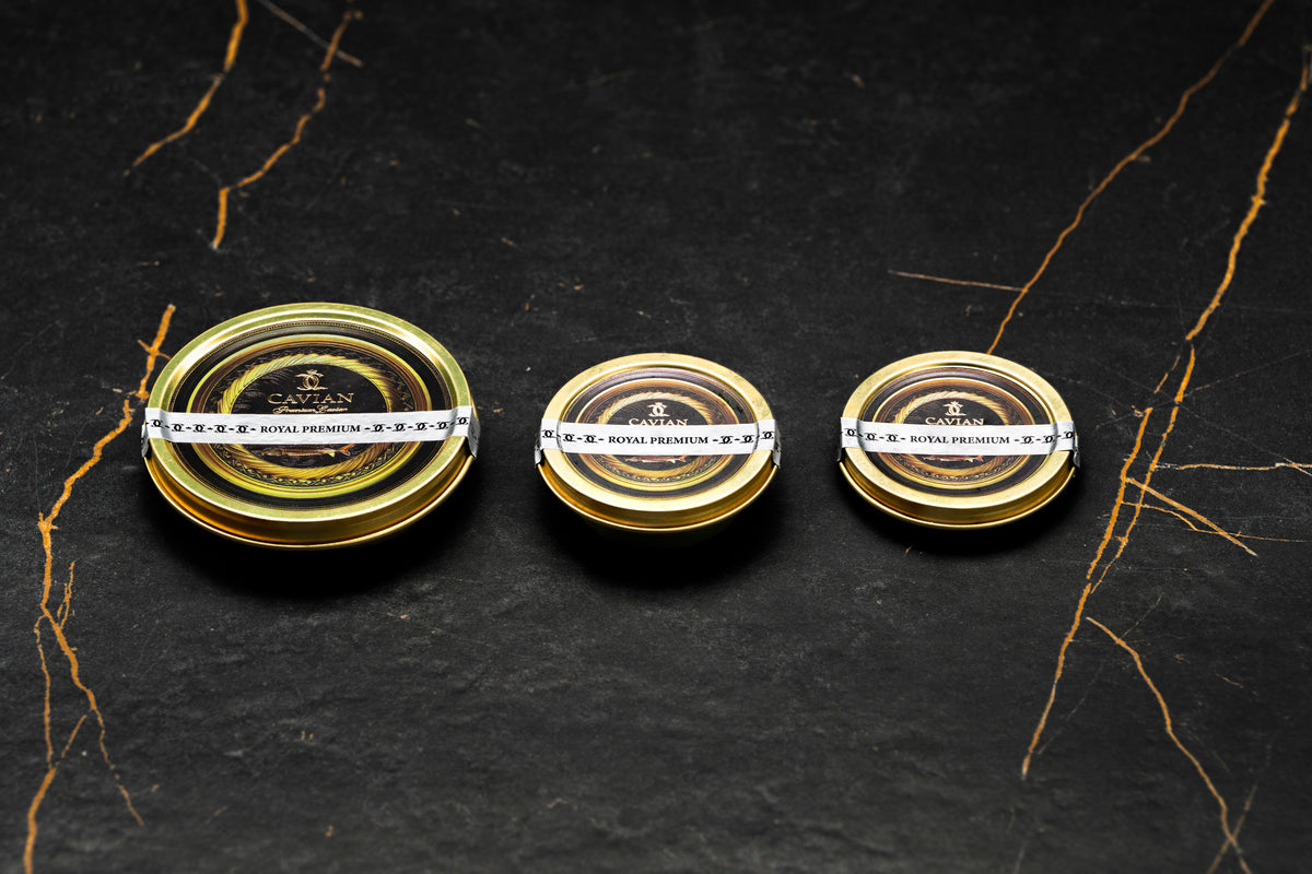 Three Cavian Royal Premium caviar tins in different sizes featuring black and gold labels with white product seals.