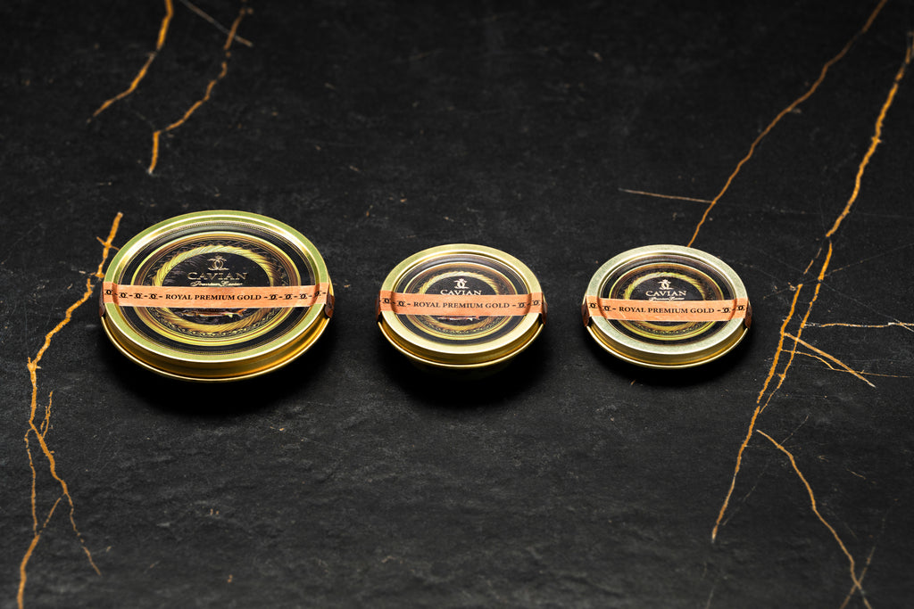 Three Cavian Royal Premium Gold caviar tins in different sizes with black and gold labels.