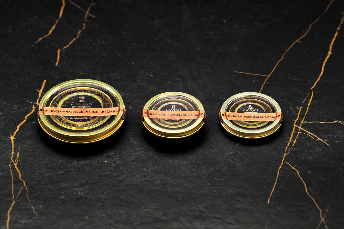 Three Cavian Royal Premium Gold caviar tins in different sizes with black and gold labels.