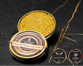Open Cavian Royal Premium Gold caviar tin with lid placed in front and award badges on a dark marble background.