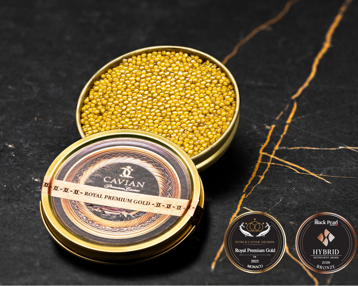 Open Cavian Royal Premium Gold caviar tin with lid placed in front and award badges on a dark marble background.
